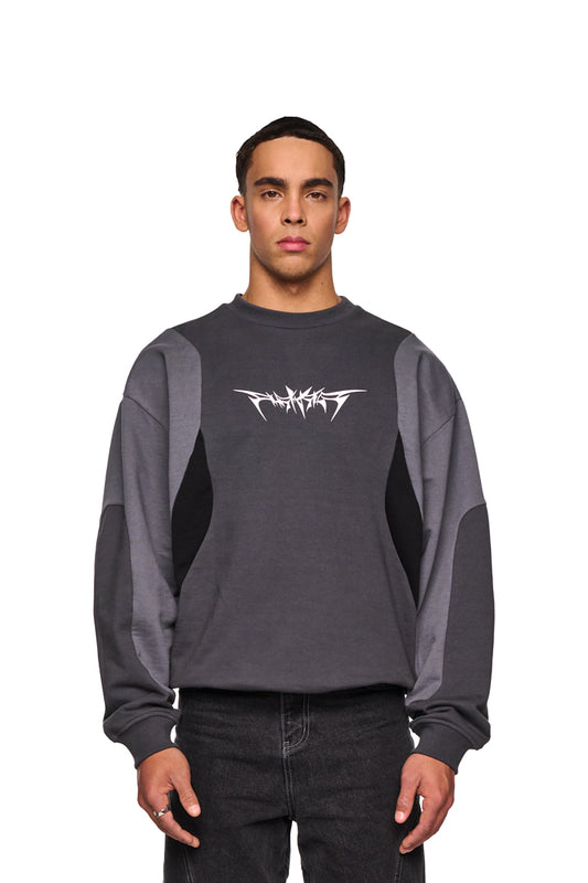 Mann trägt den Isolation Anatomy Sweater Grey mit großem weißen Thorn-Font-Print, oversized Schnitt und verschiedenen Stoffeinsätzen. Ideal für Unisex, erhältlich im OLAKALA Onlineshop.