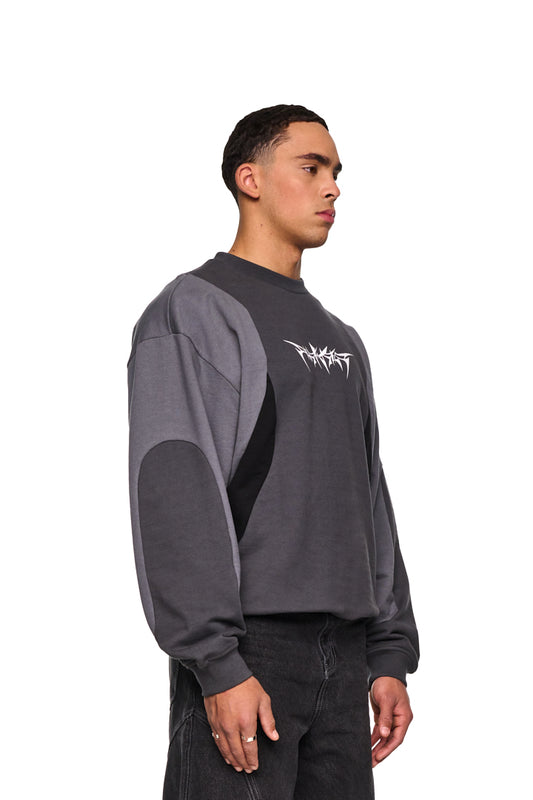 Isolation Anatomy Sweater Grey: Unisex, oversized Pullover mit großem weißen Screenprint der ISOLATION Thorn Font, Stoffeinsätze und leicht angerauter Innenseite, getragen von einem Mann.
