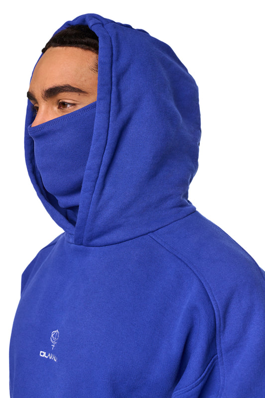 Person trägt übergroßen, blauen Discreet Mask Hoodie mit gesticktem OLAKALA-Icon auf der Brust und elastischem Saum. Unisex-Design, Kapuze inklusive Maske.