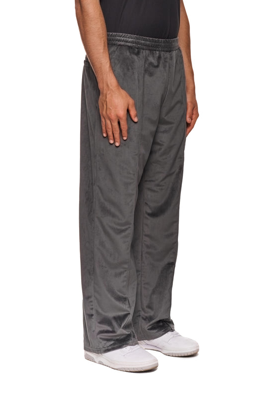 Person trägt Sports Velour Jogger Pants Gray mit offener Beinabschluss, Eingriffstaschen und gesticktem OLAKALA Sports Icon, präsentiert lockere Passform.