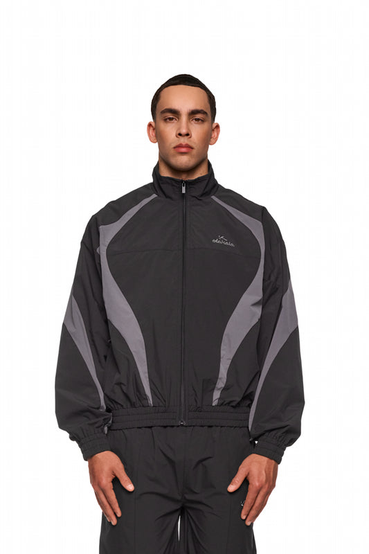 Mann trägt OLAKALA Sports Trackjacket Black mit gesticktem Logo, elastischen Bündchen und atmungsaktivem Mesh-Futter für hohen Tragekomfort.