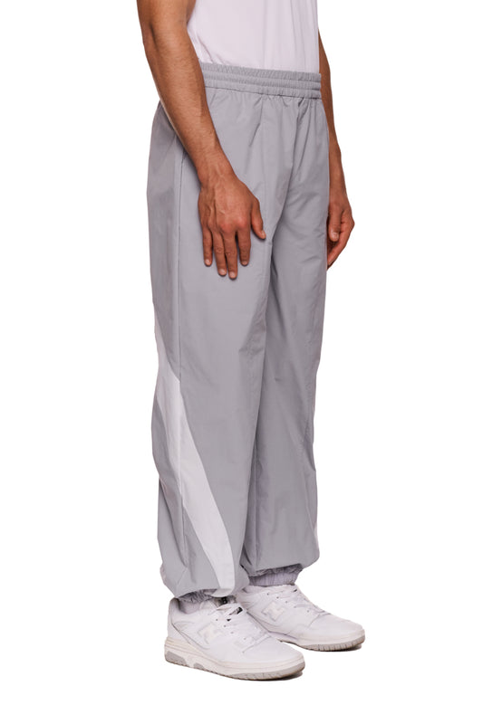 Person trägt graue Sports Trackpants aus robustem Rip-Stop-Gewebe mit OLAKALA Sports Logo am linken Bein, elastischem Bund und sportlichen Stoffeinsätzen.
