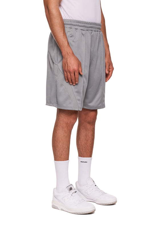 Person trägt Sports Performance Shorts Graphite mit elastischem Bund und gesticktem OLAKALA-Logo, kombiniert mit weißen Sneakers und Socken.
