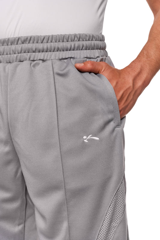 Person trägt Sports Performance Shorts Graphite mit elastischem Bund, Kordelzug und Reißverschlusstaschen, zeigt entspannte Passform und gesticktes OLAKALA-Logo.