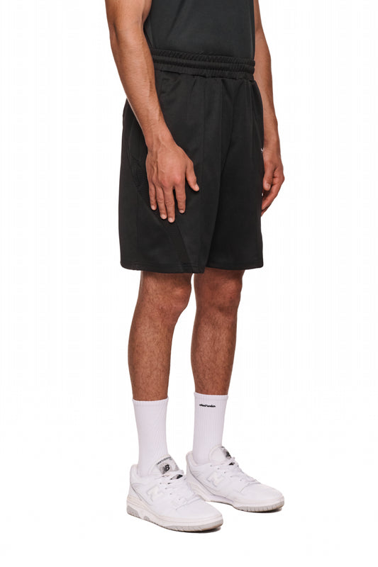 Mann trägt Sports Performance Shorts Black mit elastischem Bund und Reißverschlusstaschen, kombiniert mit weißen Sneakers und Socken.