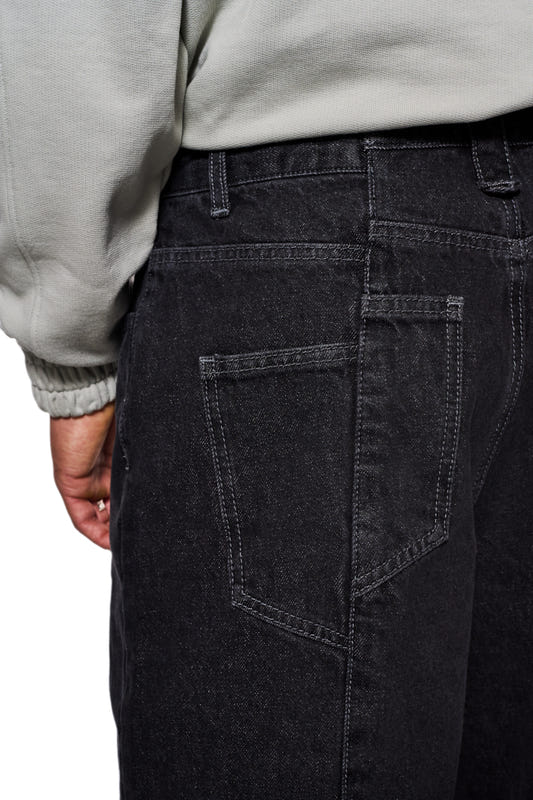 Nahaufnahme der CC Black Loose Fit Denim Pants, zeigt versetzte Gesäßtasche und gesticktes OLAKALA Logo, betont lockere Passform und charakteristische Details.