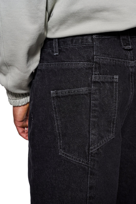 Nahaufnahme der CC Black Loose Fit Denim Pants, zeigt versetzte Gesäßtasche und gesticktes OLAKALA Logo, betont lockere Passform und charakteristische Details.