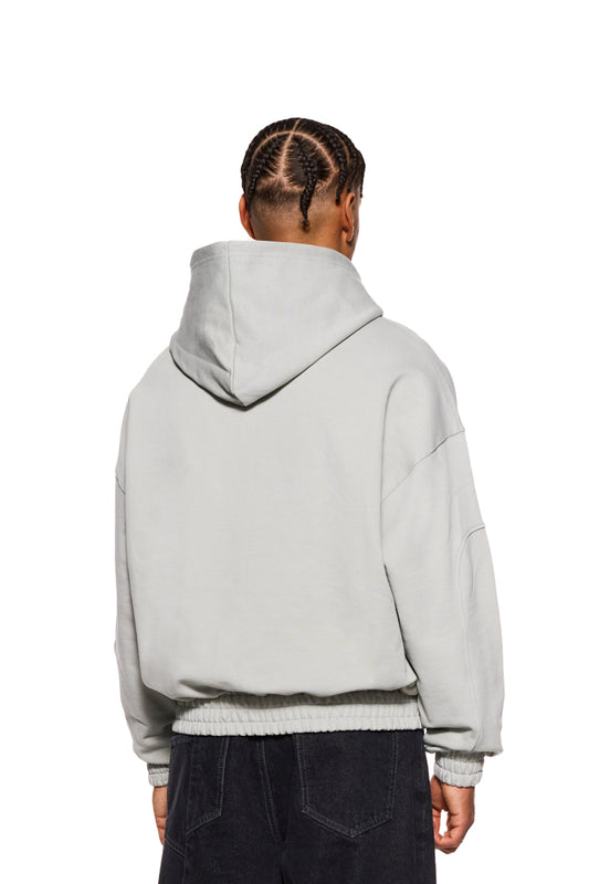 Person trägt CC Zip Hoodie Pussywillow Gray mit 2-Wege-Reißverschluss, elastischen Bündchen und gesticktem OLAKALA-Logo, oversized und unisex.