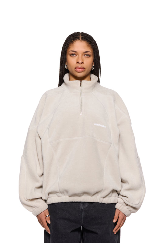 Frau trägt CC Fleece Halfzip Pussywillow Gray, oversized Unisex-Pullover mit hohem Kragen und gesticktem OLAKALA-Logo, präsentiert gemütlichen Fleece-Stoff und Reißverschluss.