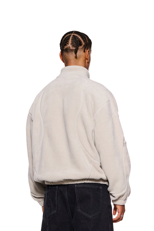 Person trägt CC Fleece Halfzip Pussywillow Gray mit hohem Kragen und gesticktem OLAKALA Logo, zeigt elastische Bündchen und Reißverschluss auf der Brust.