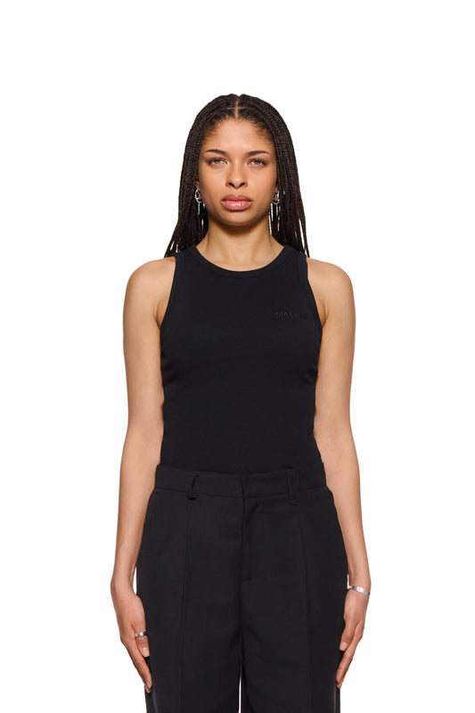 Frau mit geflochtenem Haar trägt eng anliegendes CC Fine Rib Tanktop Black mit gesticktem OLAKALA Logo auf der linken Brust.