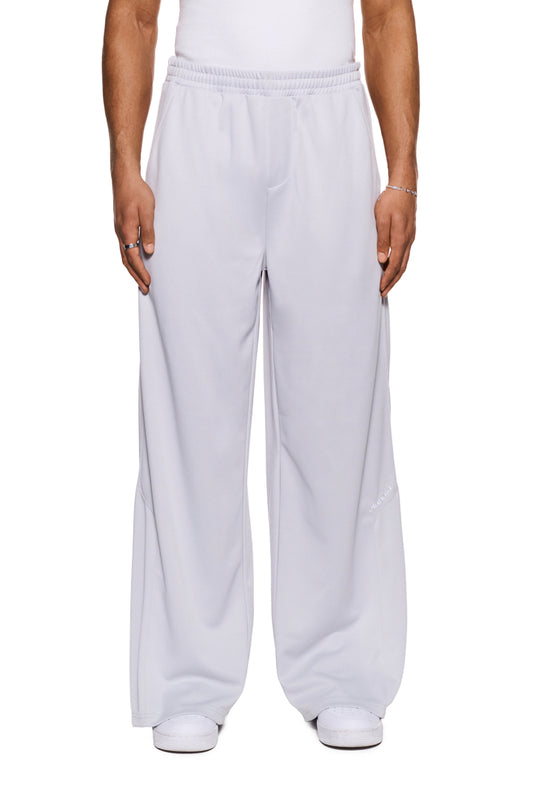 Person trägt CC Jogger Pants mit französischen Eingriffstaschen und elastischem Bund, gesticktes OLAKALA Logo sichtbar, lockere Passform.