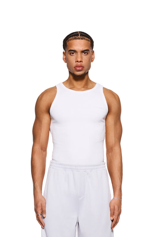 Mann in einem eng anliegenden, weißen CC Fine Rib Tanktop mit gesticktem OLAKALA-Logo auf der Brust, präsentiert die Passform und den schweren Rippstoff.