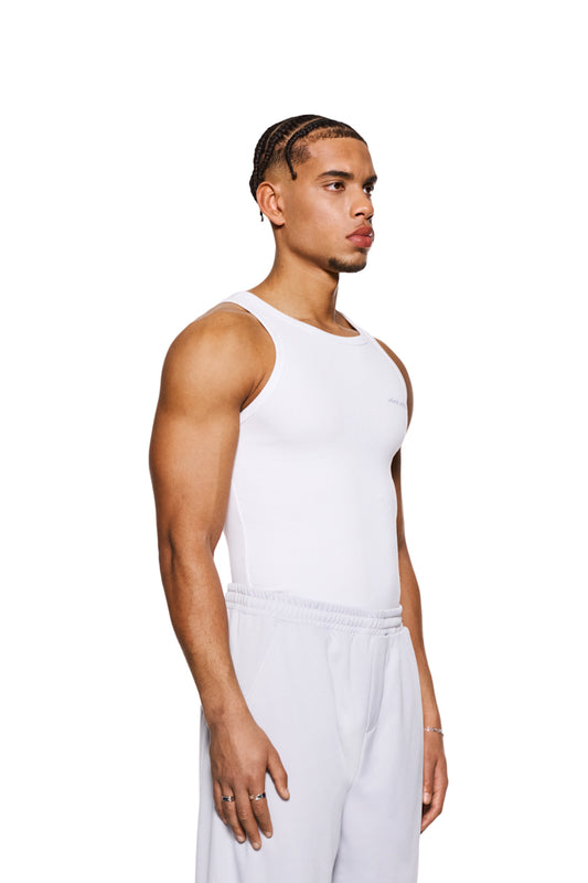 Mann in weißem CC Fine Rib Tanktop mit gesticktem OLAKALA Logo auf der Brust, zeigt eng anliegende Passform und schweren Ripp-Stoff.