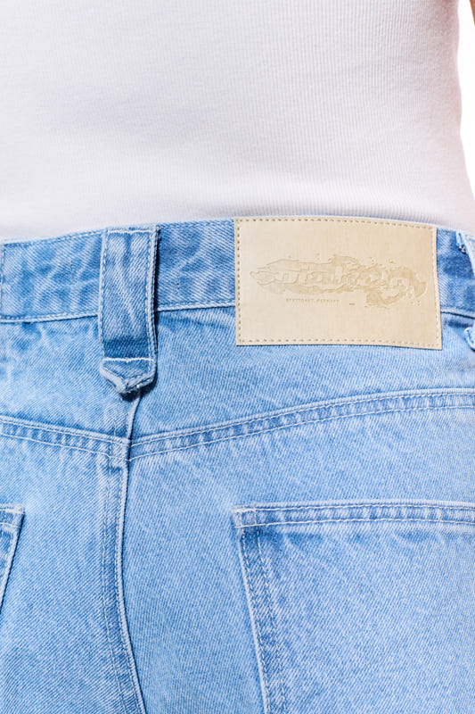 Close-up of the CC Blue Loose Fit Denim Pants with offset waistband, 5-pocket design and embossed OLAKALA patch on the waistband.