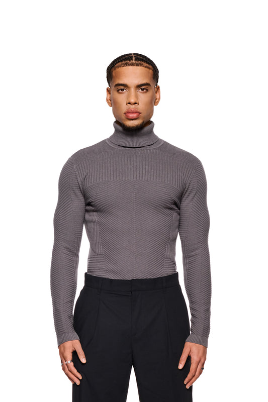 Mann trägt Anatomy Turtleneck Gray mit Rollkragen und engem Schnitt, präsentiert Strickmuster und OLAKALA-Tag am Kragenrücken.