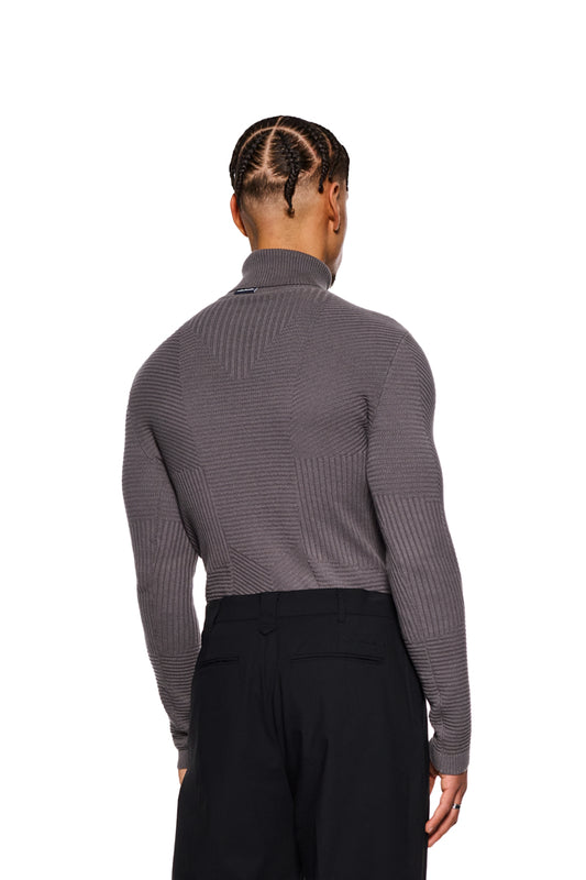 Mann trägt Anatomy Turtleneck Gray, eng anliegenden Strickpullover mit Rollkragen von OLAKALA. Perfekt für lässige Anlässe.