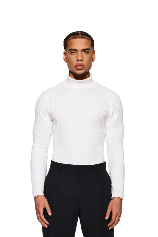 Mann in engem weißen Anatomy Turtleneck mit Rollkragen von OLAKALA, betont durch verschiedene Strickmuster, trägt schwarze Hose.
