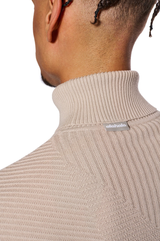 Nahaufnahme eines Mannes mit Rollkragenpullover, betont die Passform des Anatomy Turtleneck Beige mit OLAKALA-Tag am Kragen.