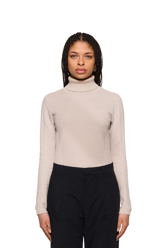 Frau trägt einen Anatomy Turtleneck Beige mit Rollkragen und OLAKALA Tag. Enganliegende Passform, präsentiert als Unisex-Strickpullover.
