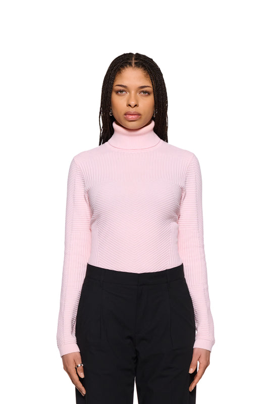 Frau trägt einen OLAKALA Anatomy Turtleneck Pink mit Rollkragen und enger Passform. Der Strickpullover zeigt verschiedene Strickmuster.
