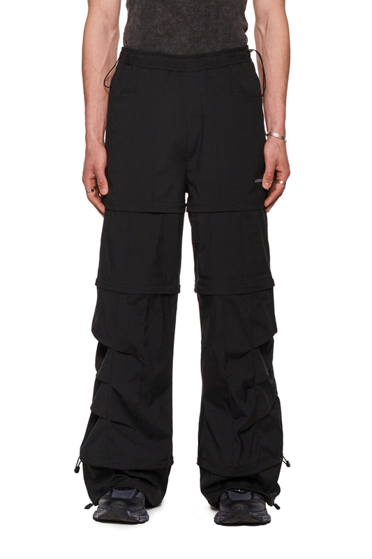 Person trägt Gills Zip-Off Pants Black mit abnehmbaren Beinteilen und elastischem Bund, präsentiert lockere Passform und robuste Rip-Stop-Qualität.