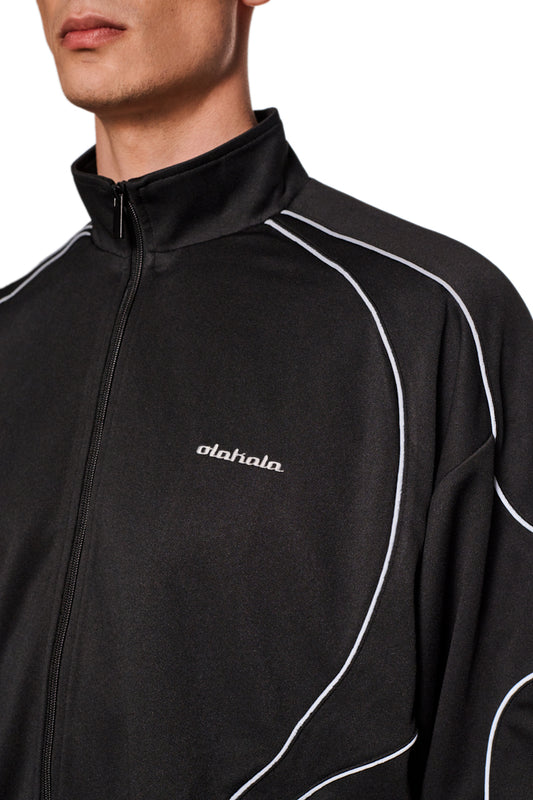 Nahaufnahme der Rave Trackjacket mit Stehkragen, vorderem Reißverschluss, reflektierenden Teilungsnähten und gesticktem OLAKALA-Logo auf der linken Brust.