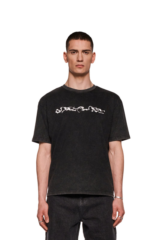 Mann trägt E.O.I. T-Shirt Black mit Ripp-Kragen und Siebdruck-Grafik vorne, reguläre Passform, unisex, präsentiert im OLAKALA Onlineshop.