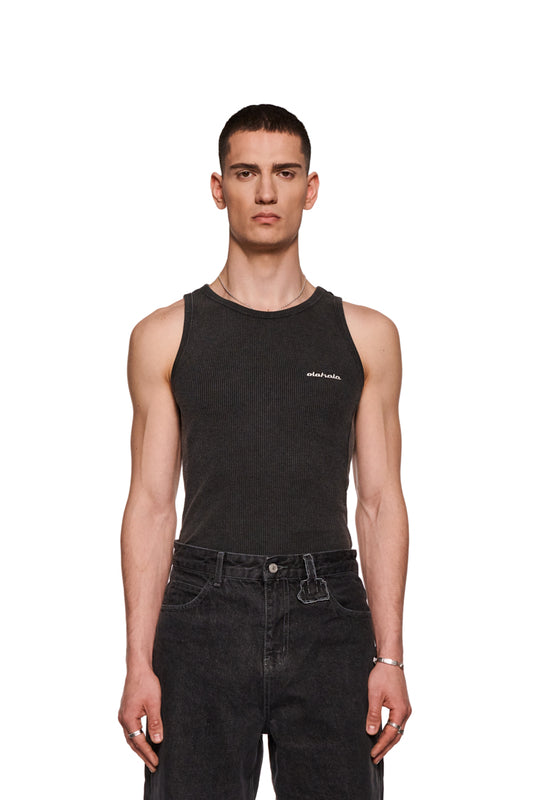 Mann trägt E.O.I Tanktop Black mit gesticktem OLAKALA-Logo auf der Brust und Teilungsnähten an den Seiten, betont muskulös, eng anliegend.