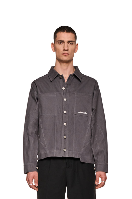 Mann trägt Heavy Anatomy Cotton Overshirt Grau mit Knopfleiste, Teilungsnähten und gesticktem OLAKALA-Logo auf Brusttasche. Robustes Köper-Gewebe, lockere Passform, unisex.