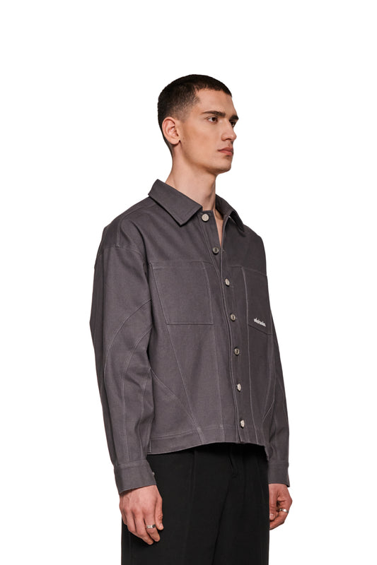 Mann trägt Heavy Anatomy Cotton Overshirt Gray mit Knopfleiste und gesticktem OLAKALA-Logo auf Brusttasche, sichtbar sind Teilungsnähte und Manschetten.