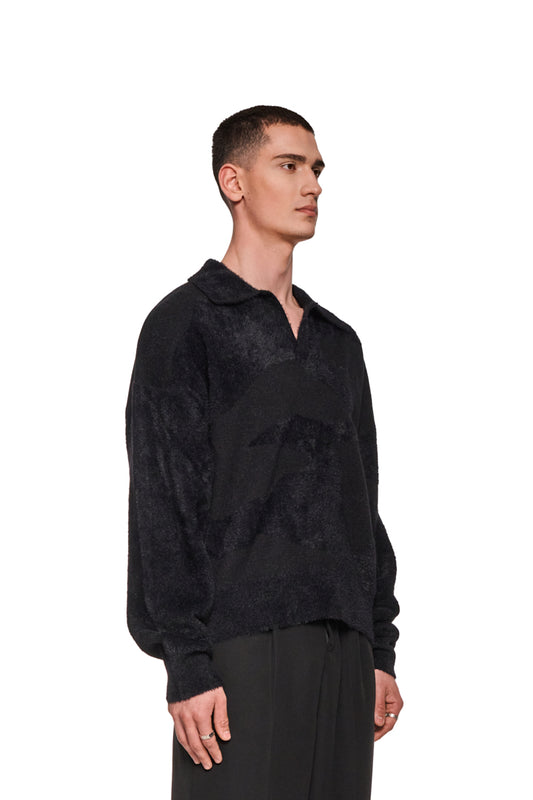 Mann im Glitched Fuzzy Polo Black mit Polo-Kragen und gesticktem Synergy-Logo, zeigt die reguläre Passform und Ripp-Bündchen.