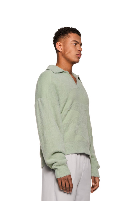 Ein Mann trägt einen grünen Glitched Fuzzy Polo Mint mit Polokragen und gesticktem Synergy-Logo auf der Brust, unisex, reguläre Passform.