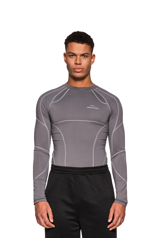 Mann trägt das Sports Anatomy Tech Top Dark Gray mit Ziernähten und OLAKALA Logo auf der Brust, eng anliegendes Unisex-Design.