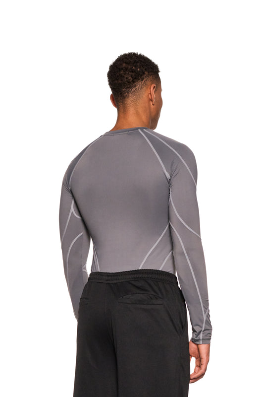 Mann trägt das Sports Anatomy Tech Top Dark Gray mit Ziernähten und OLAKALA Logo auf der Brust, kombiniert mit schwarzen Hosen.