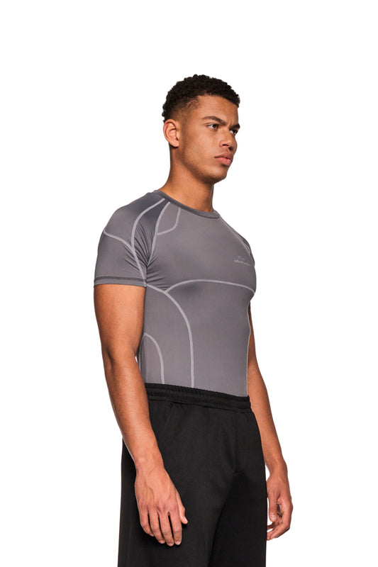 Mann in grauem Sports Anatomy T-Shirt mit Ziernähten und OLAKALA Logo auf der Brust, eng anliegend, unisex.