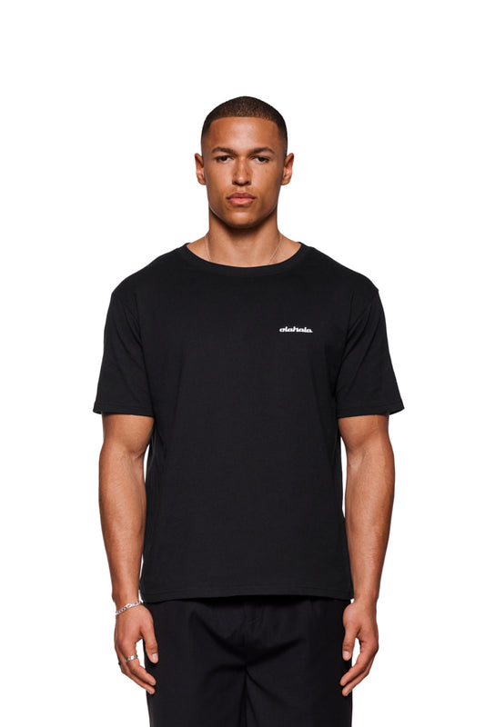 Mann im CC T-Shirt Regular Black mit Ripp-Kragen und gesticktem OLAKALA-Logo auf der Brust, reguläre Passform, unisex Design.