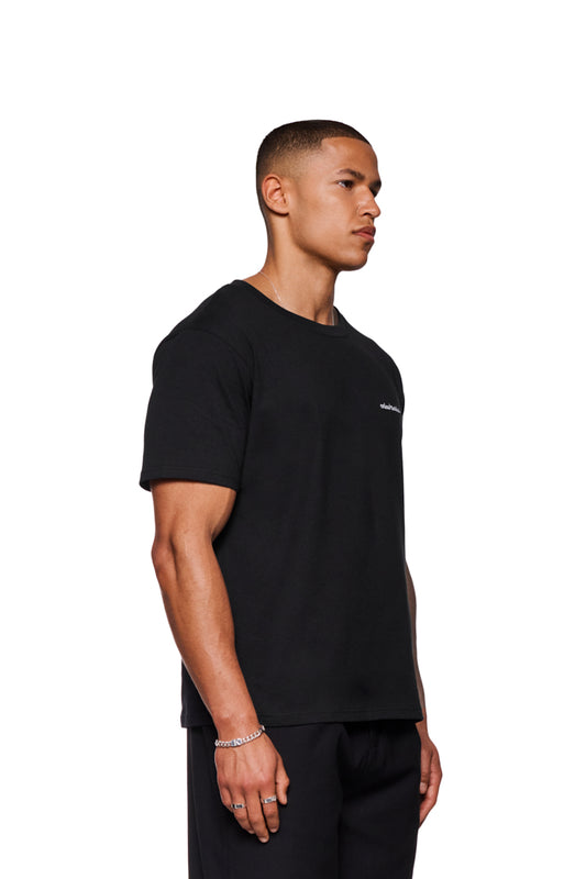 Mann im CC T-Shirt Regular Black mit gesticktem OLAKALA Logo auf der Brust, trägt silbernes Armband und Ringe.