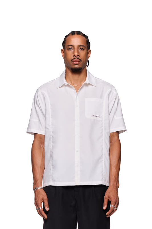 Man wears the CC short sleeve shirt white by OLAKALA with button placket, logo embroidery on chest pocket, lightweight fabric and loose fit.