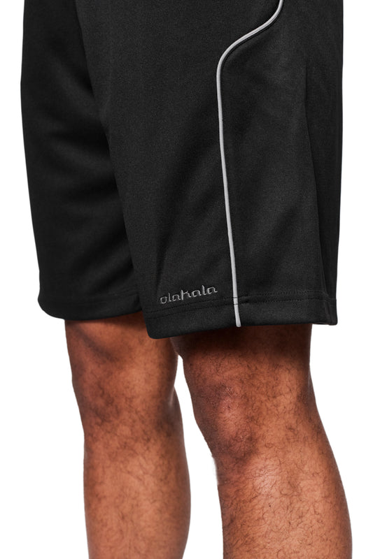 Nahaufnahme eines Mannesbeins mit schwarzer CC Shorts von OLAKALA, zeigt Logo-Stickerei, paspelierte Seitennaht, französische Taschen und elastischen Bund.
