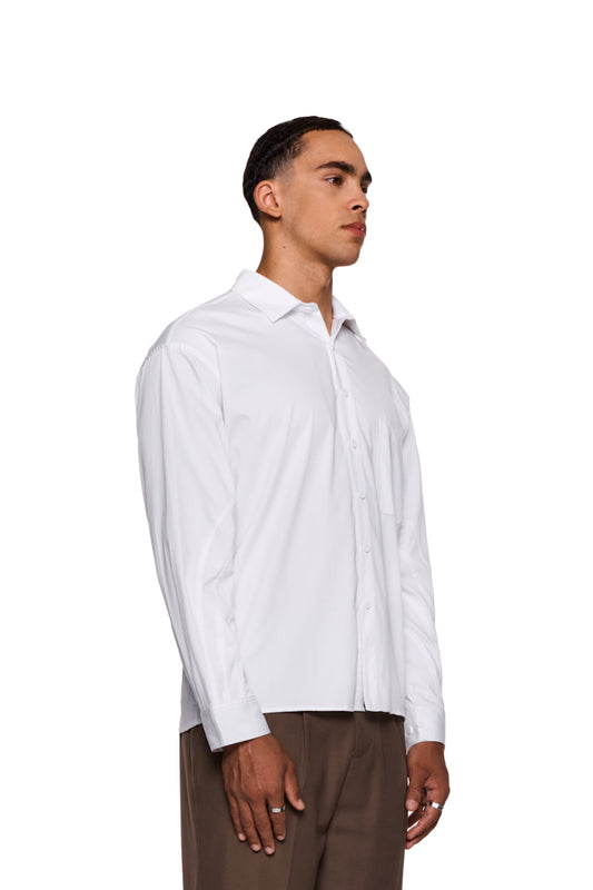 Mann trägt das CC Anatomy Shirt White mit Knopfleiste, doppellagigem Kragen, aufgesetzter Tasche mit OLAKALA-Logo und lockerer Passform. Nahaufnahme einer Hand mit Ring.