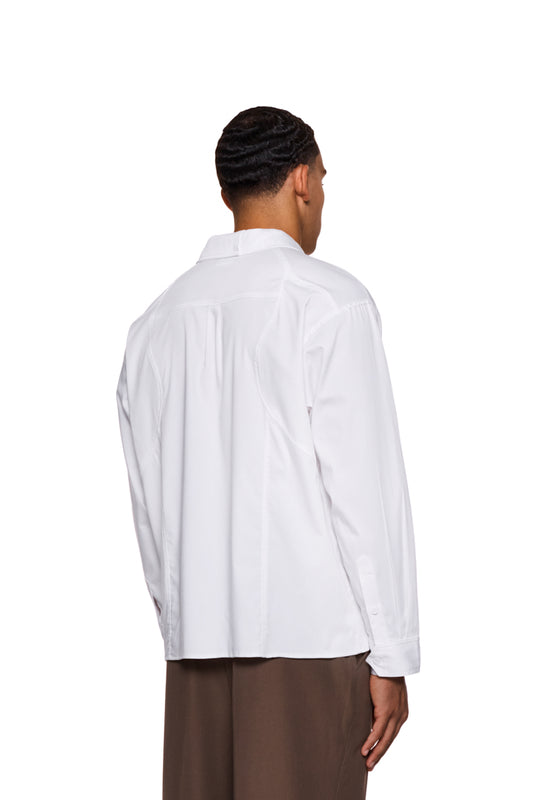 Mann trägt das CC Anatomy Shirt White mit Knopfleiste, doppellagigem Kragen und gesticktem OLAKALA-Logo auf der Brusttasche. Lockerer, unisex Schnitt.