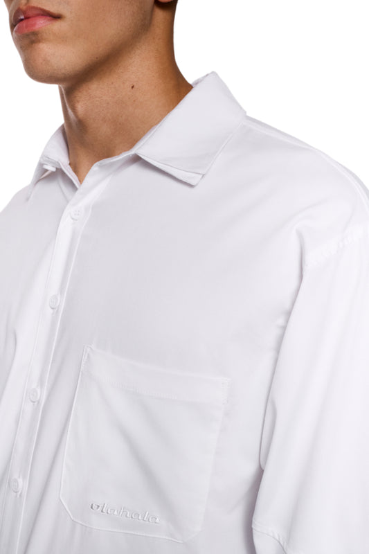 Nahaufnahme eines Mannes mit dem CC Anatomy Shirt White, das eine Knopfleiste, doppellagigen Kragen und gesticktes OLAKALA Logo aufweist.