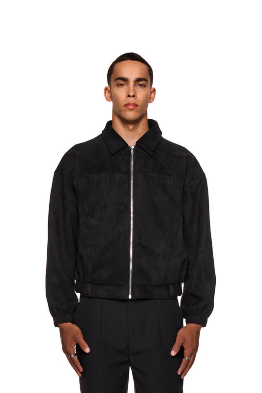 Man wears CC Anatomy Velour Jacket Black with double-layer collar, asymmetrical back and embroidered OLAKALA logo. Hands in piped pockets, elasticated cuffs visible.