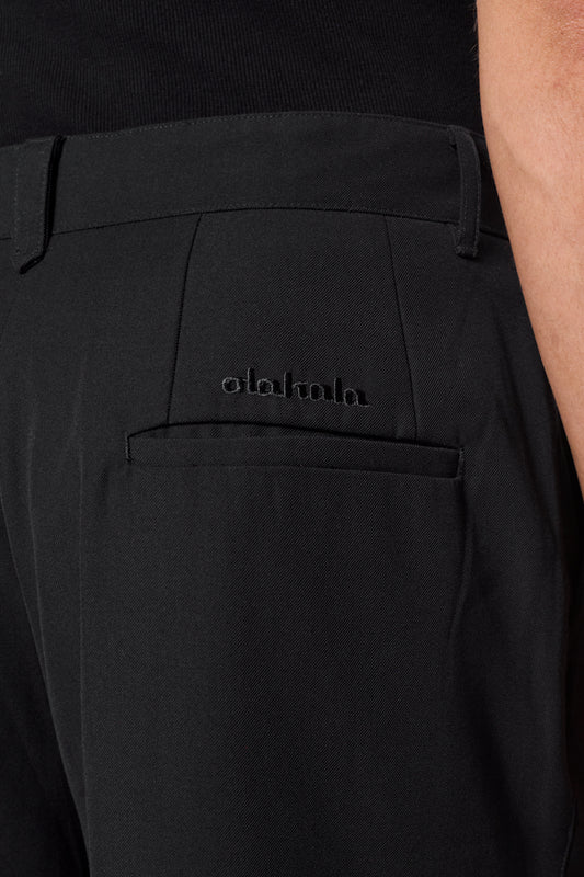 Nahaufnahme der CC Dress Pants Regular Black mit französischen Taschen, OLAKALA-Logo über der Gesäßtasche und weichem Köper-Gewebe.