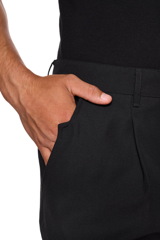 Hand in der Tasche einer schwarzen CC Dress Pants Regular mit asymmetrischem Eingriff, Bundfalten und gesticktem OLAKALA Logo über der Gesäßtasche.