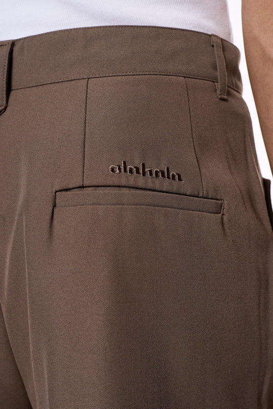 Nahaufnahme der CC Dress Pants Regular Brown mit asymmetrischer Tasche, Paspeltaschen, gesticktem OLAKALA-Logo und robustem Köper-Gewebe. Unisex-Design für vielseitigen Stil.