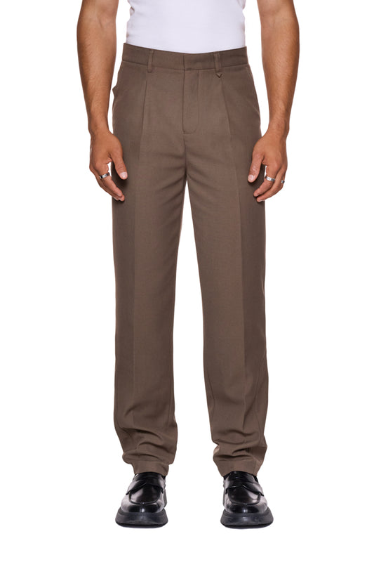 Mann trägt CC Dress Pants Slim Fit Brown mit französischen Taschen und gesticktem OLAKALA-Logo, schmale Passform, aus weichem, robustem Köper-Gewebe.