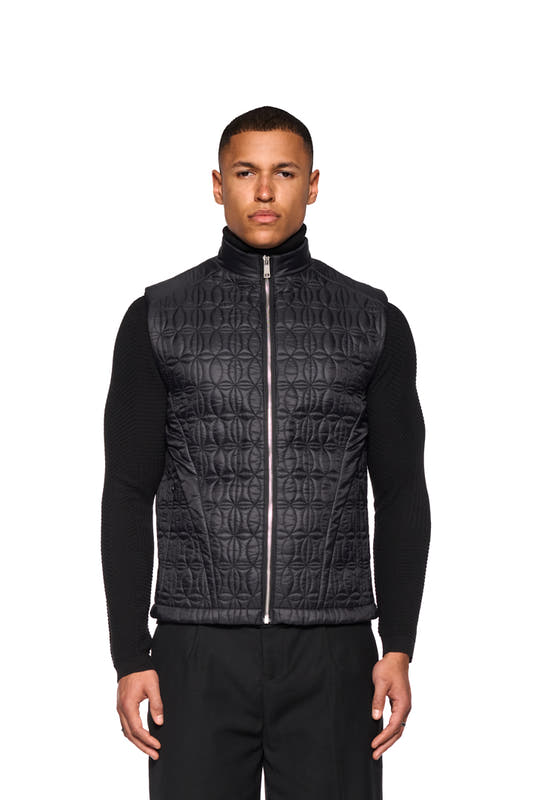 Man wears Gilet Vest Black with stand-up collar and OLAKALA logo print. Visible zippers and slit pockets accentuate the design.