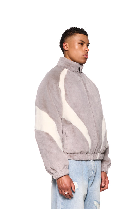 Mann trägt Plüschjacke mit Stehkragen und farbigen Einsätzen. Die Jacke hat Raglanärmel, Reißverschluss, Eingriffstaschen und elastische Bündchen.